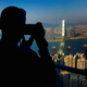A visitor to Victoria Peak takes photographs of buildings on Hong Kong Island and Kowloon